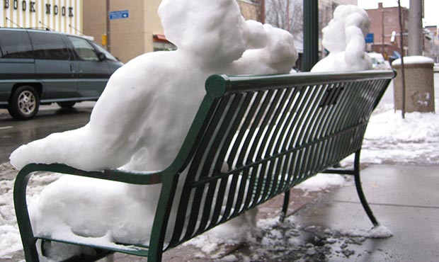 Snowpeople reclining on a Pullman Bench with Back