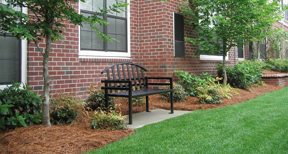 McConnell Bench with Back situated among landscaped flora